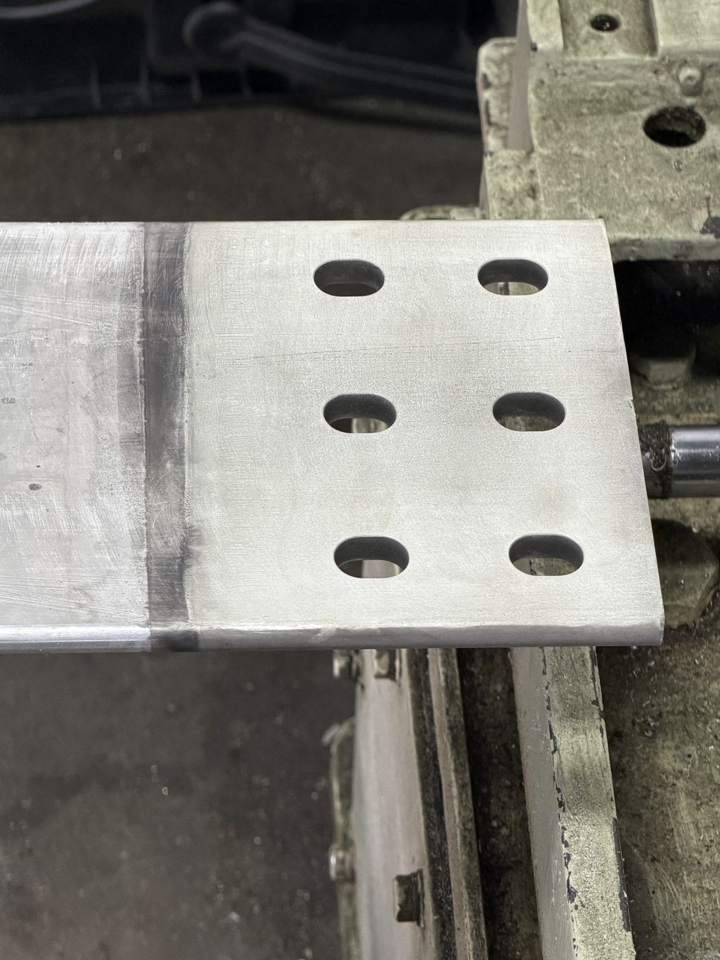 Close-up of an aluminum generator bus bar end pad in the Southern Switch machine shop, freshly machined contact surface with bolt pattern.