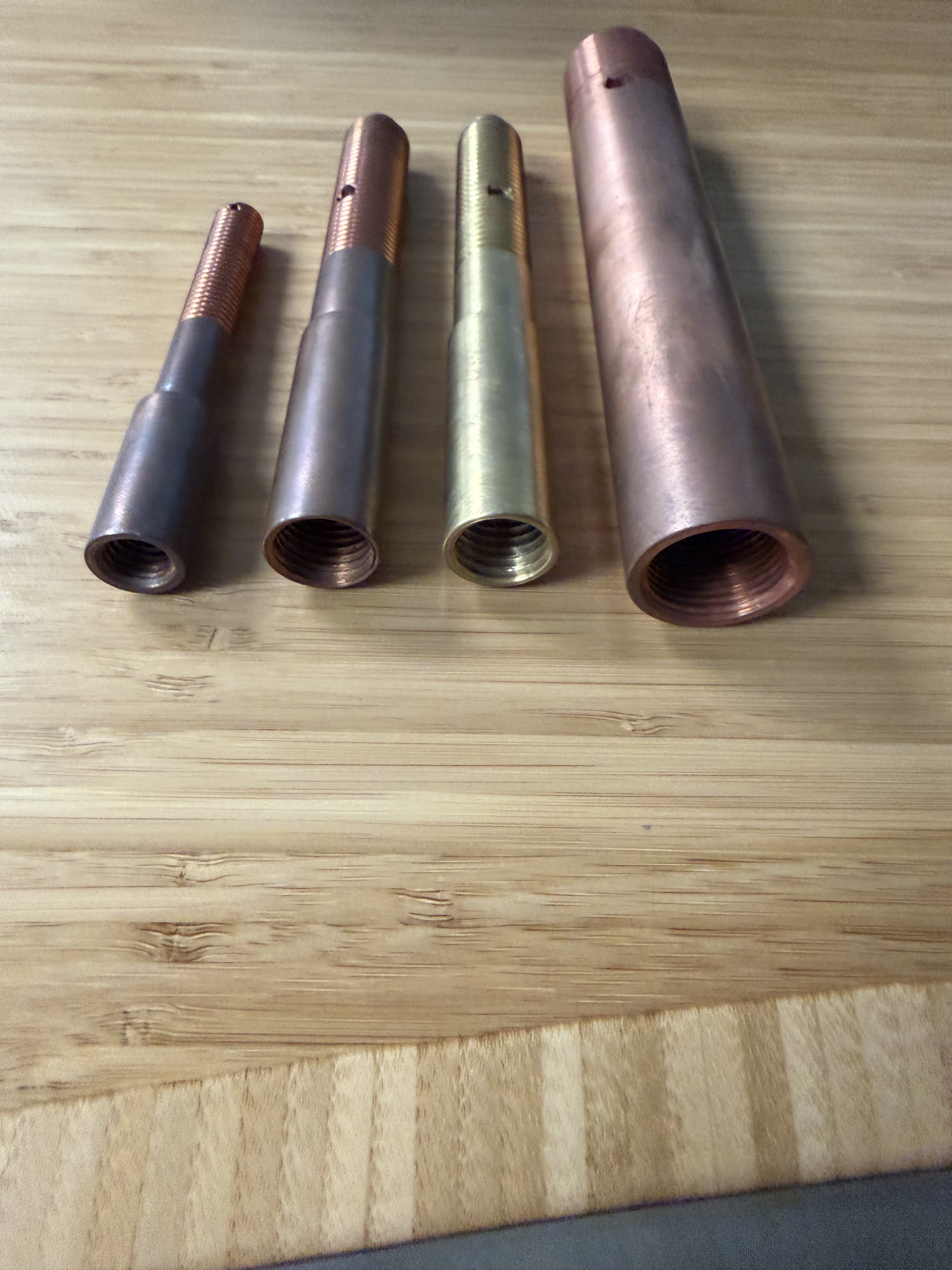 Bottom view of four transformer bushing draw lead extensions showing the internal female threads, the connection point to the transformer winding draw lead.