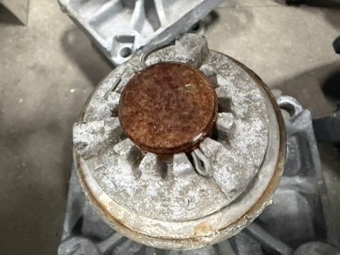 As-received Southern States EV2 rotating bearing showing the castellated aluminum lock nut bloomed white with oxide and the rusted steel shaft end at the center, the dissimilar-metal corrosion that seizes the bearing