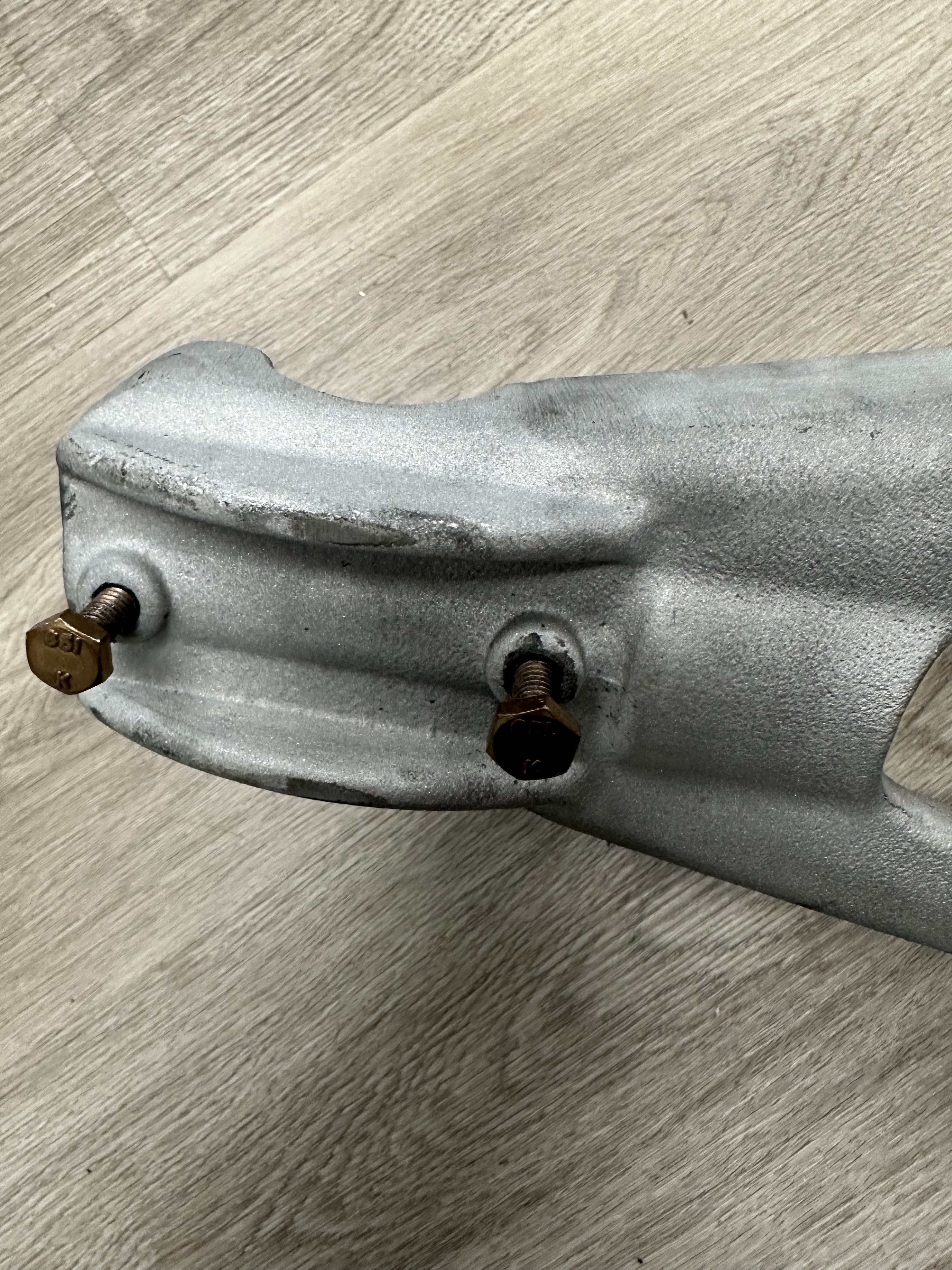 Top end of EV2 linkage arm showing two brass hex-head set screws with thread sealant applied. Grade marking visible on fastener heads.