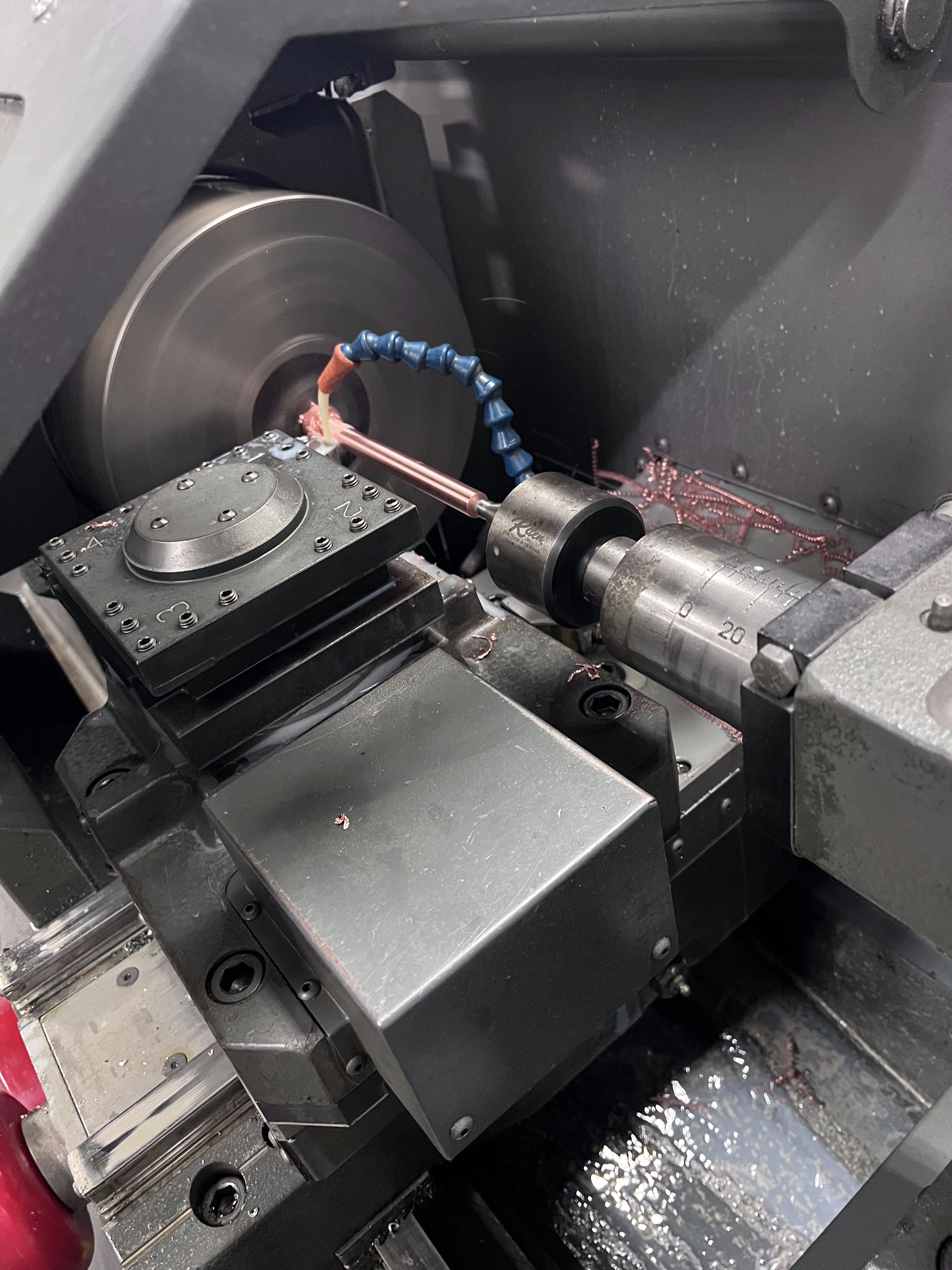 CNC lathe turning a copper rod to .405 inch diameter for FPL emergency mobile transformer hookup. Copper shavings visible from the cutting operation. Southern Switch machine shop, Palm Harbor, FL.