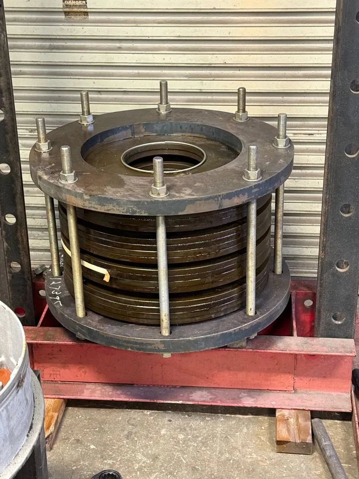 The disc spring held compressed in our custom-built jig under a 60-ton press, required before the mechanism can be removed.
