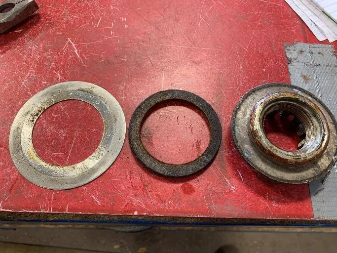 The original bottom seal: a stainless-steel shim over a felt gasket. The felt had degraded and was holding water against the bearing.